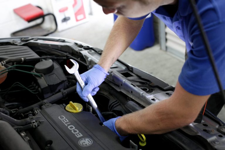 Our Services - Repairs Image of a technician holding a spanner and working under the hood of a car